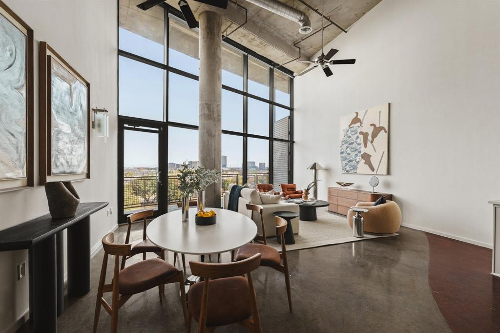 Polished concrete flooring, exposed concrete ceiling, industrial-style ceiling fan, full-height window wall with dark framing, and a concrete structural column