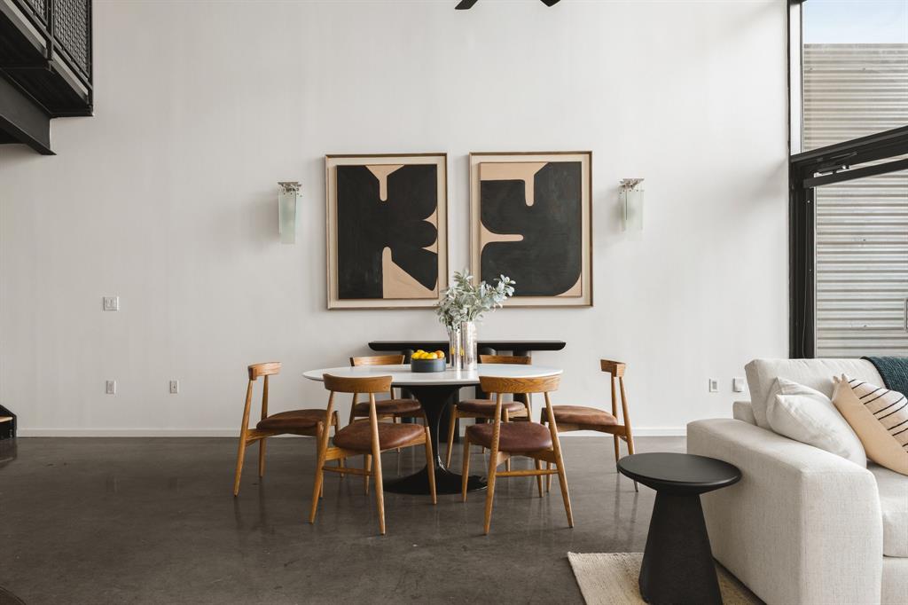 Polished concrete flooring, high ceilings, custom wall sconces, and a black steel open staircase