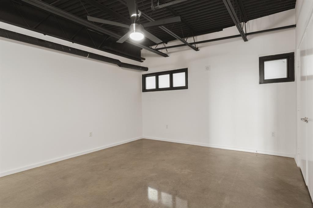 Exposed black ceiling joists, concrete flooring, and multiple high windows