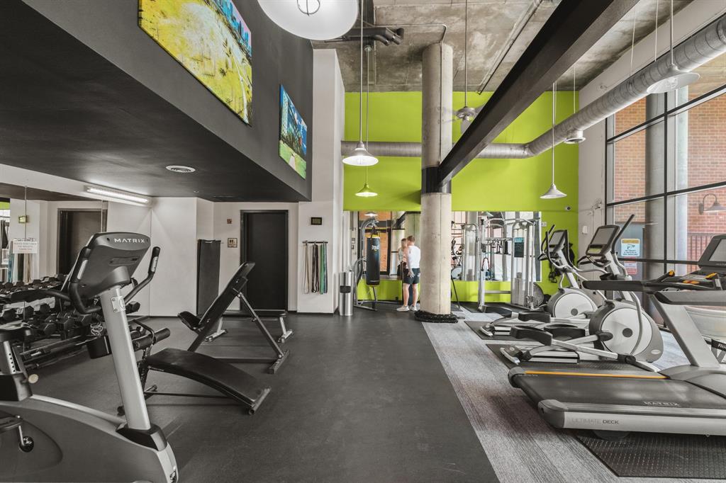 Fitness center with exposed ceiling, large windows, recessed and pendant lighting, and durable flooring