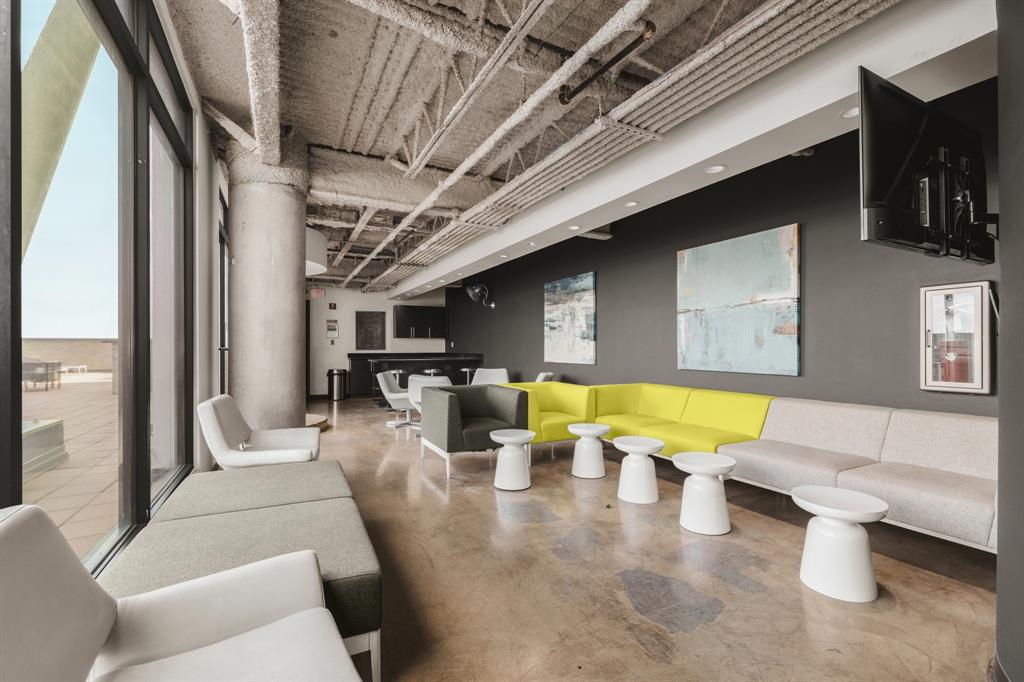 Expansive window line, exposed structural ceiling, polished concrete flooring, built-in bar area, and recessed lighting