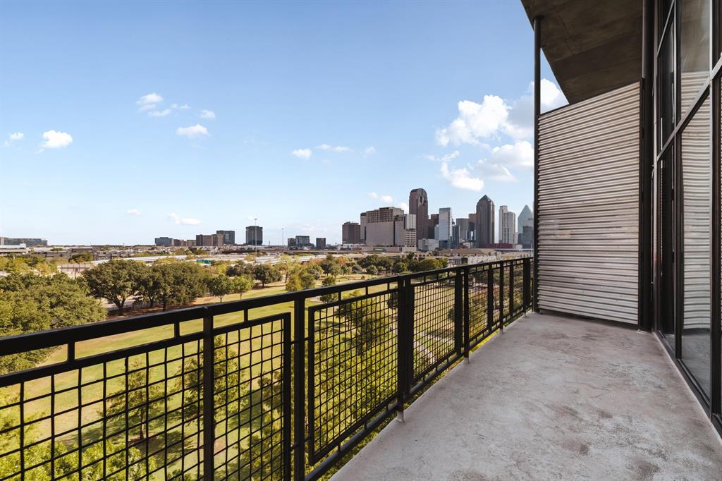 Concrete balcony with black metal railings, offering urban skyline and green space scenery
