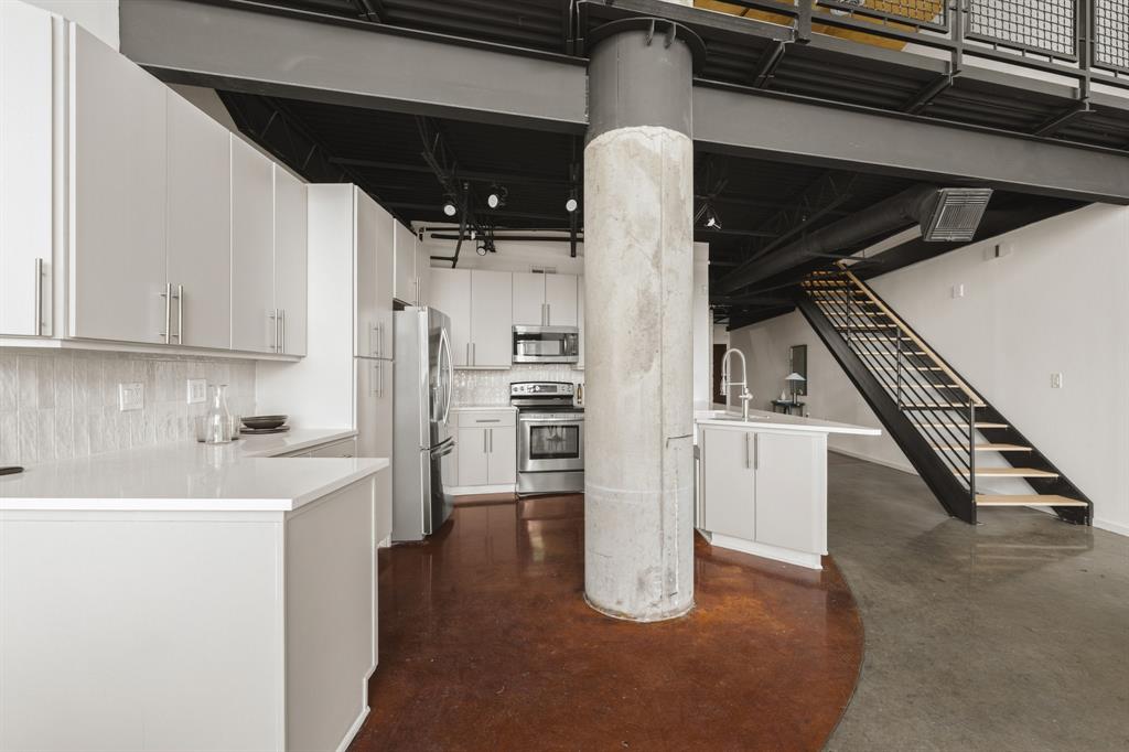 Open-concept kitchen with light cabinetry, stainless steel appliances, and solid surface countertops