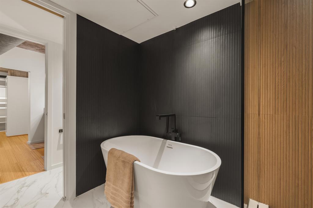 Freestanding soaking tub with matte black fixtures, set against a dark fluted accent wall