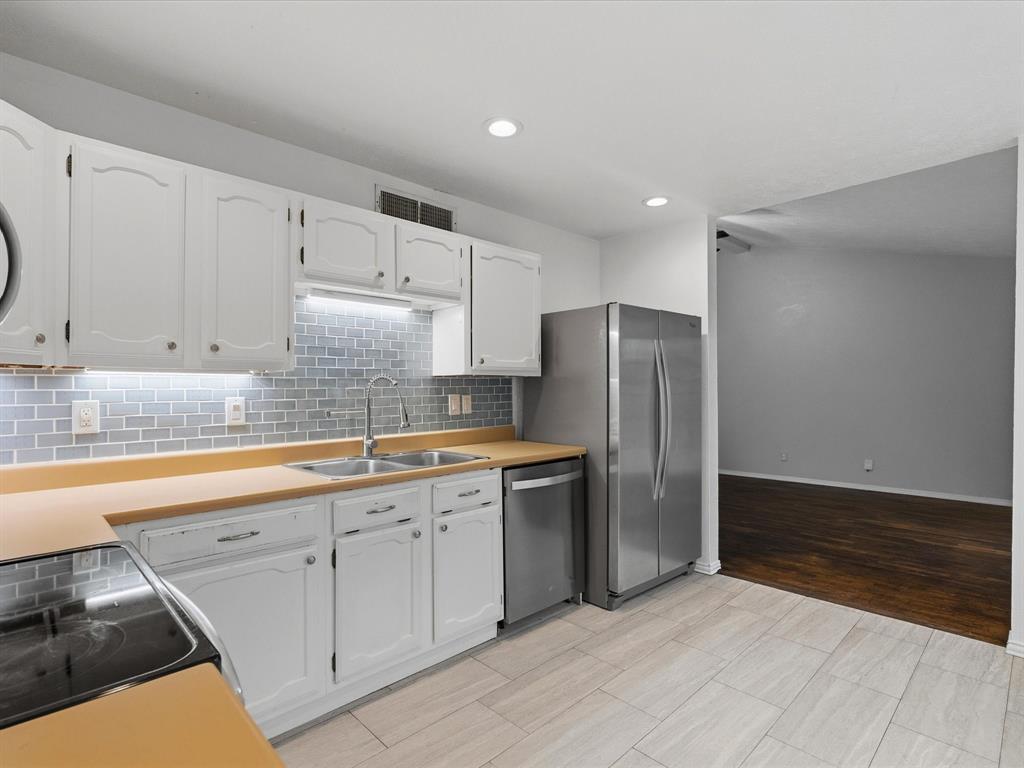 Kitchen featuring white cabinetry, stainless steel appliances, subway tile backsplash, solid-surface countertops, and tile flooring