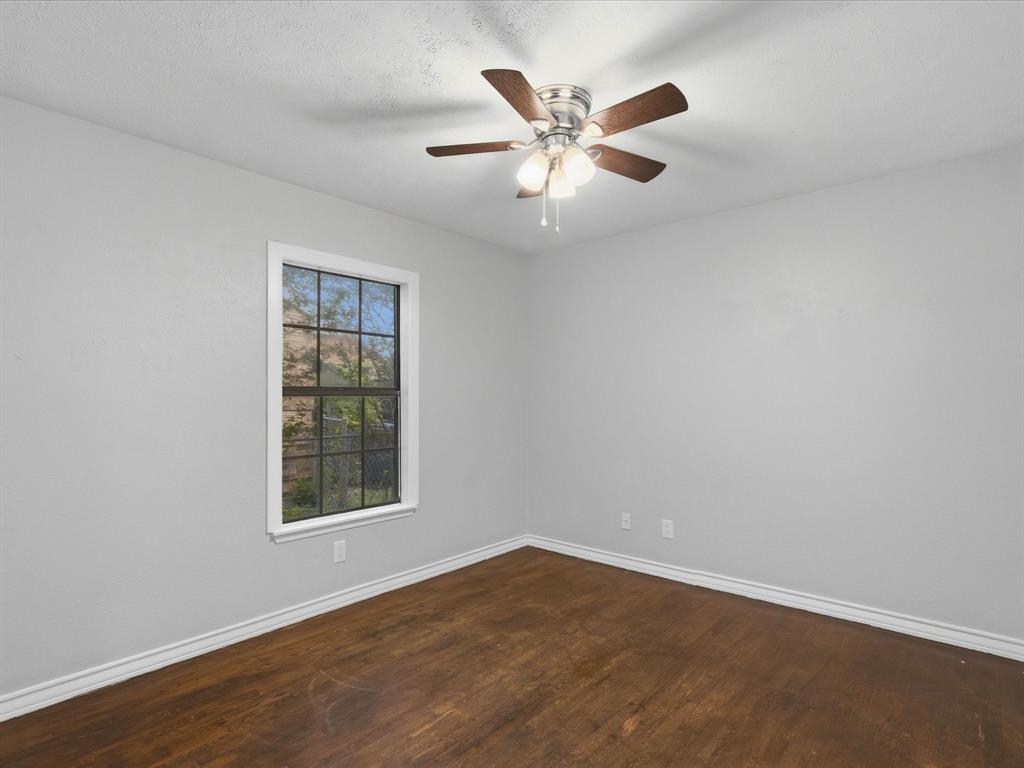 Room featuring wood-finish flooring, a multi-pane window with a white frame, and a ceiling fan with integrated lighting