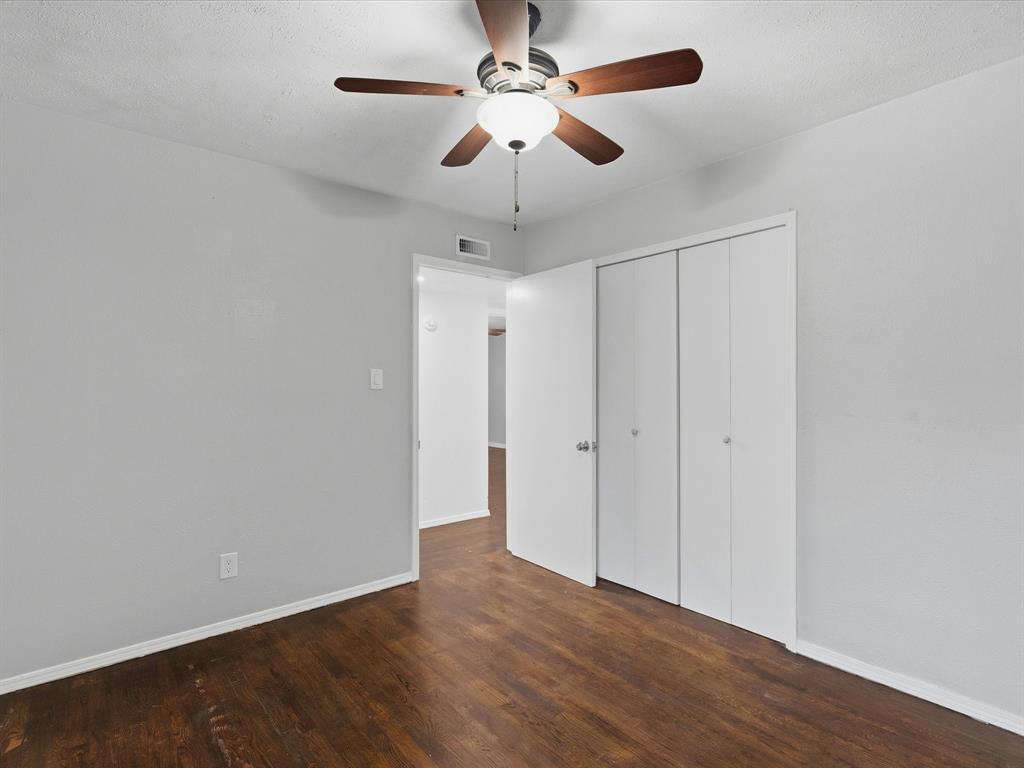 Interior room featuring wood-finish flooring, a ceiling fan with integrated lighting, and a double-door closet