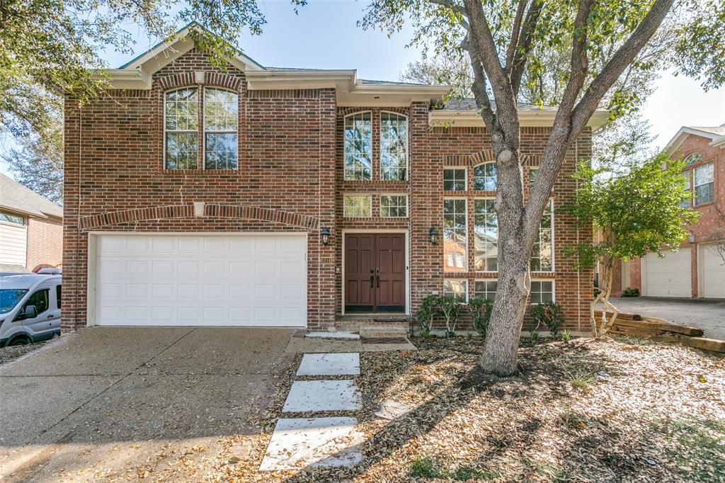 Two-story brick exterior featuring a double-door entryway, multi-pane arched windows, and an attached two-car garage