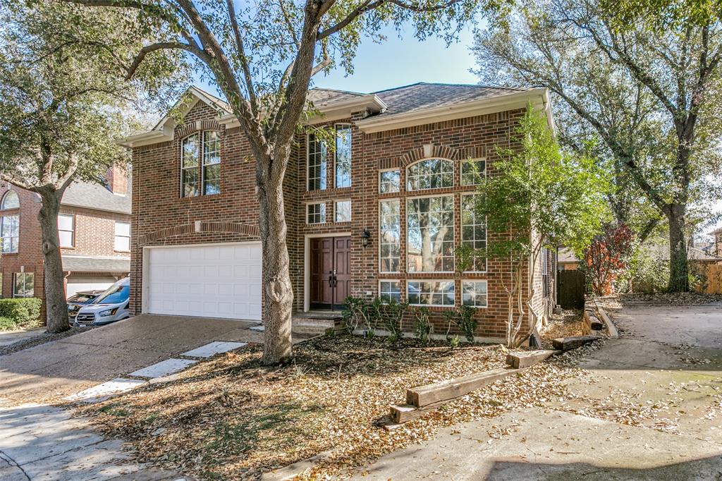 Two-story brick exterior featuring an arched entryway, multi-pane windows, and an attached two-car garage