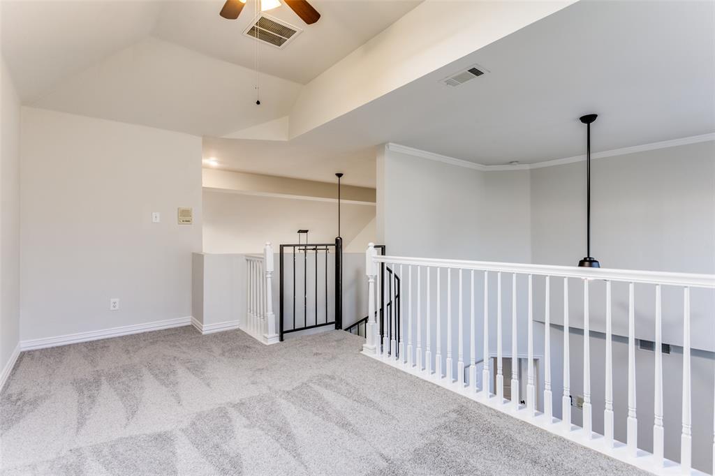 Vaulted ceiling, carpeted flooring, and white railing featuring a metal accent panel