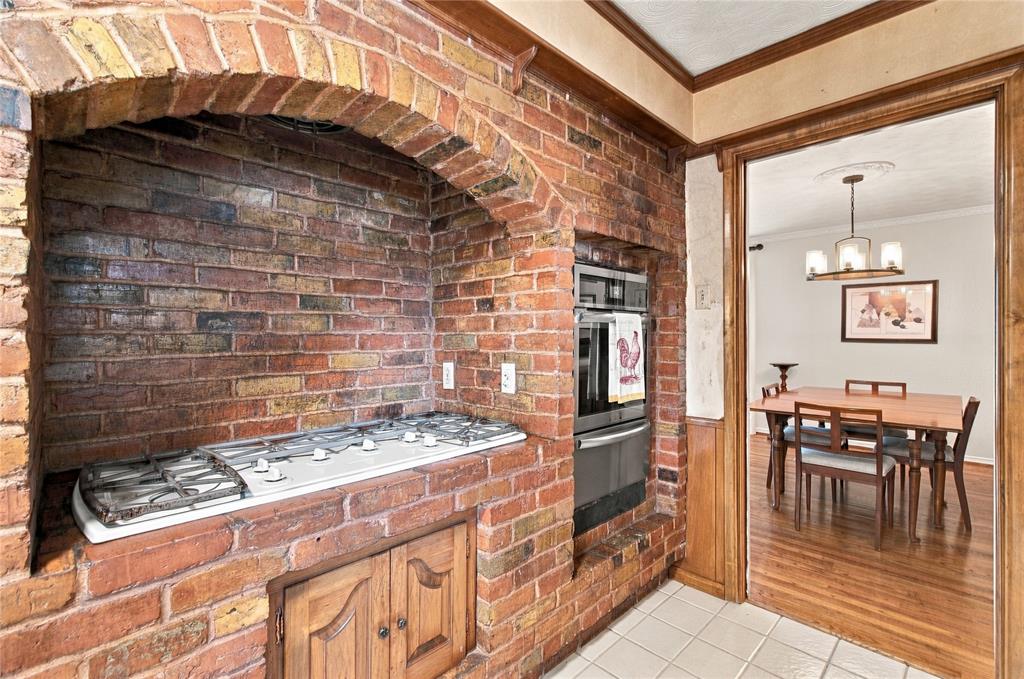 Exposed brick arched cooking alcove featuring a built-in gas cooktop, integrated stainless steel wall oven, and wood-paneled cabinetry Exposed brick arched cooking alcove featuring a built-in gas cooktop, integrated stainless steel wall oven, and wood-paneled cabinetry