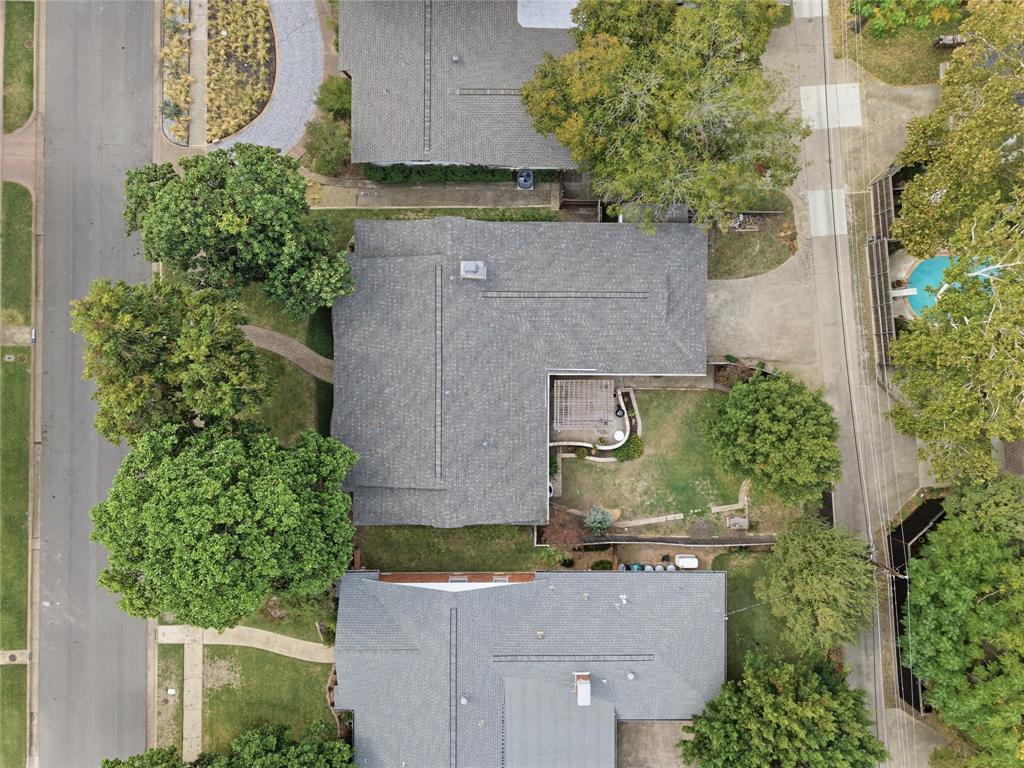 Aerial perspective of a property featuring mature trees, a private backyard with a pergola, and hardscaped exterior grounds