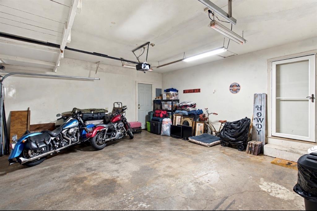 Garage interior featuring concrete flooring, overhead fluorescent lighting, and a walk-out utility door
