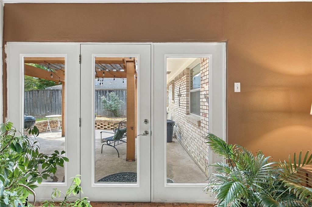 Glass-paned door system featuring dual sidelights and a brick exterior facade with an attached wooden pergola