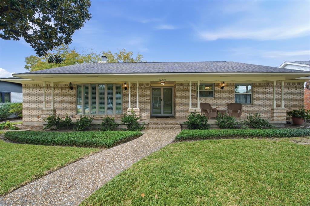 Single-story brick exterior featuring a covered front porch, multi-pane bay window, and aggregate concrete walkway Single-story brick exterior featuring a covered front porch, multi-pane bay window, and aggregate concrete walkway