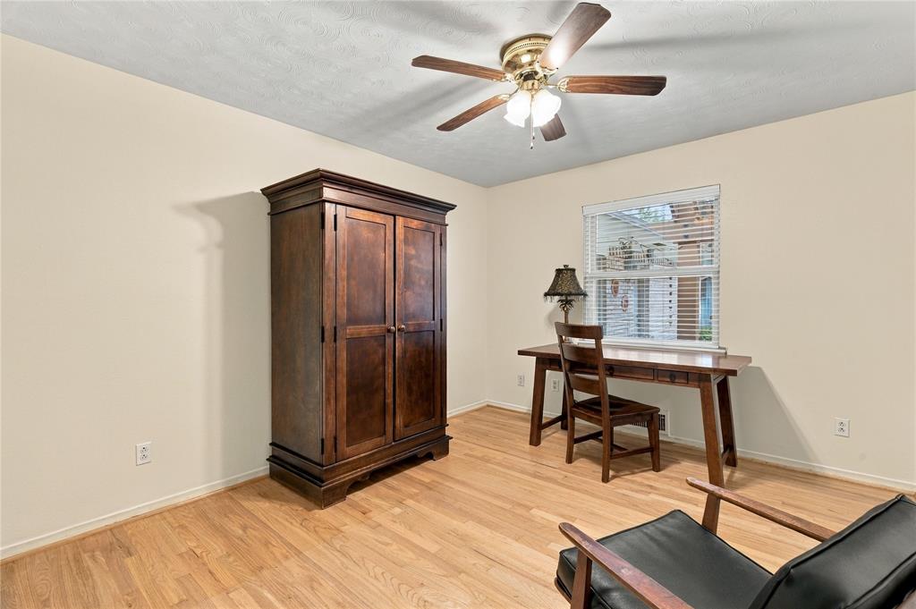Room featuring wood-finish flooring, a ceiling fan with integrated light fixture, and horizontal blind window treatments