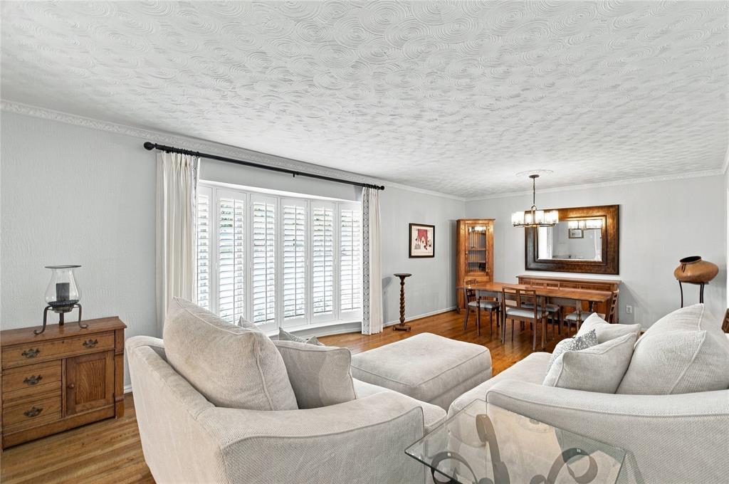 Bay window with integrated shutters, wood-finish flooring, ceiling with textured finish, and crown molding Bay window with integrated shutters, wood-finish flooring, ceiling with textured finish, and crown molding