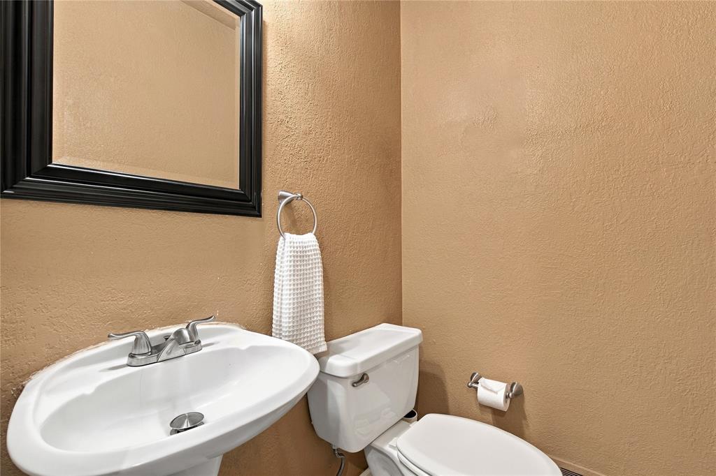 Pedestal sink with dual-handle faucet, wall-mounted mirror with black frame, and wall-mounted ring towel holder