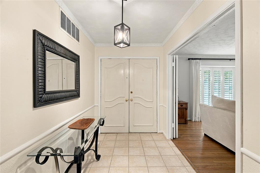 Foyer featuring double entry doors, tile flooring, crown molding, and a geometric pendant light fixture Foyer featuring double entry doors, tile flooring, crown molding, and a geometric pendant light fixture