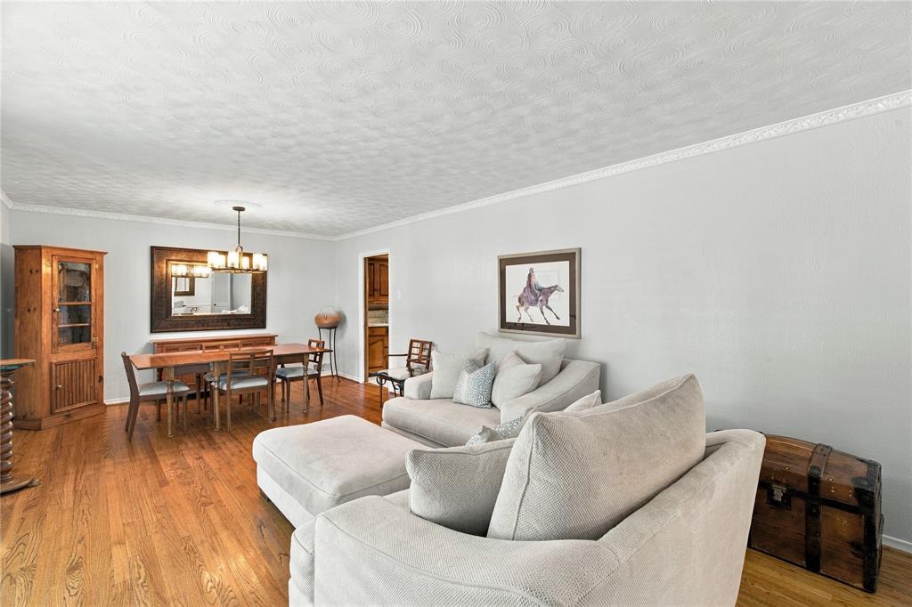 Wood-finish flooring, textured ceiling, crown molding, and a multi-light hanging chandelier Wood-finish flooring, textured ceiling, crown molding, and a multi-light hanging chandelier