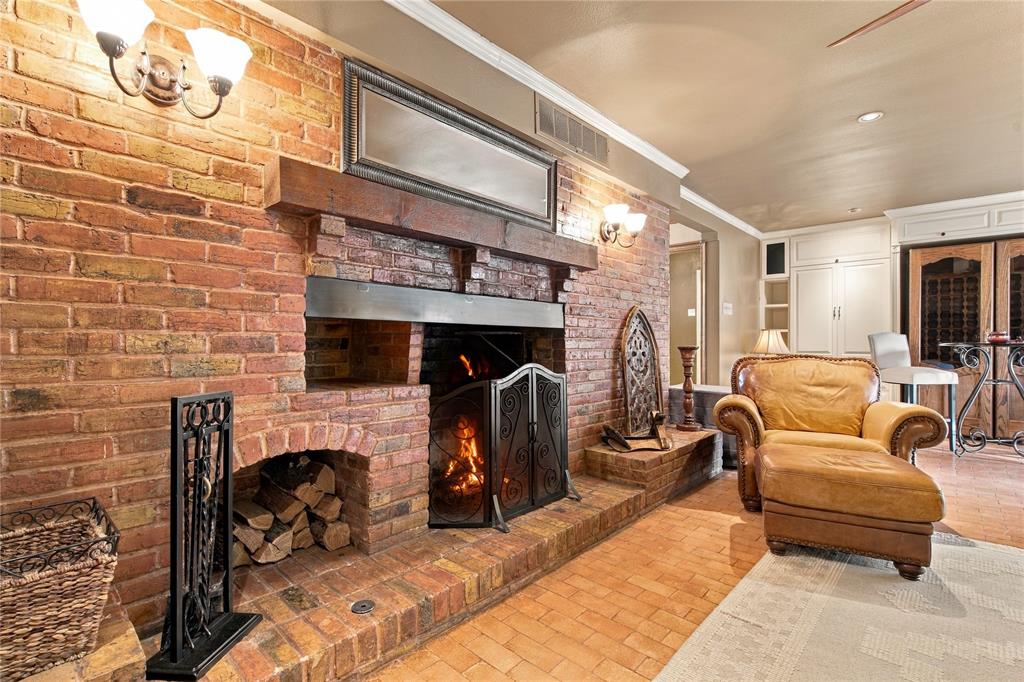 Exposed brick fireplace featuring a wood beam mantel, recessed storage nook, and raised brick hearth