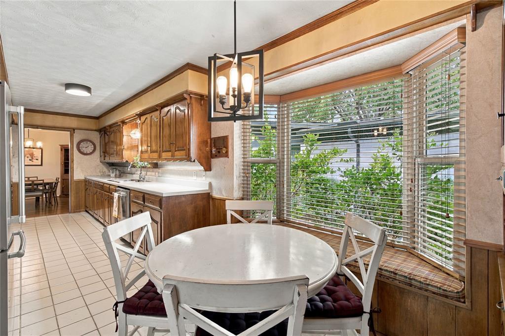 Kitchen featuring wood cabinetry, solid surface countertops, tile flooring, and a bay window with a built-in window seat Kitchen featuring wood cabinetry, solid surface countertops, tile flooring, and a bay window with a built-in window seat