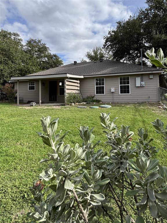 Rear exterior featuring horizontal lap siding, a covered patio, and a spacious grass yard with mature perimeter trees