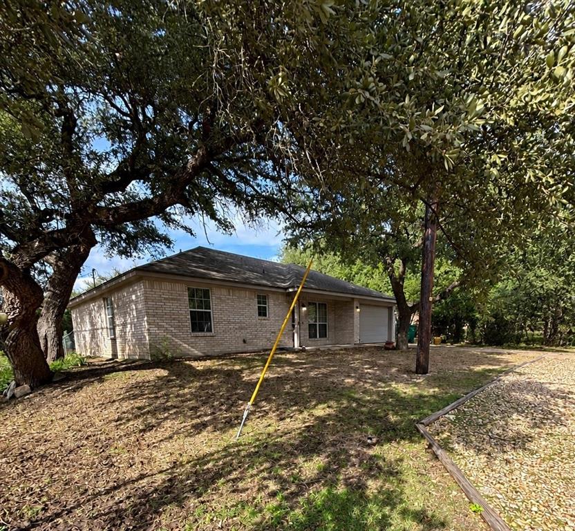 Single-story masonry exterior with a hip roof, multi-car garage, and mature trees on a lot with perimeter landscaping Single-story masonry exterior with a hip roof, multi-car garage, and mature trees on a lot with perimeter landscaping