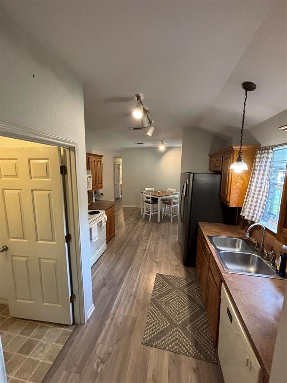 Kitchen featuring wood-finish flooring, wood cabinetry, dual-basin stainless steel sink with faucet, and overhead track lighting Kitchen featuring wood-finish flooring, wood cabinetry, dual-basin stainless steel sink with faucet, and overhead track lighting