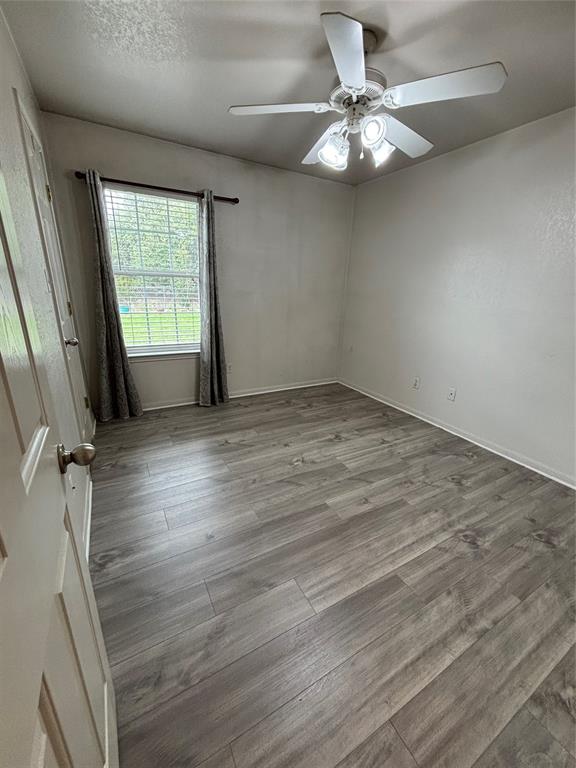 Wood-finish flooring, ceiling fan with integrated lighting, and single-pane window