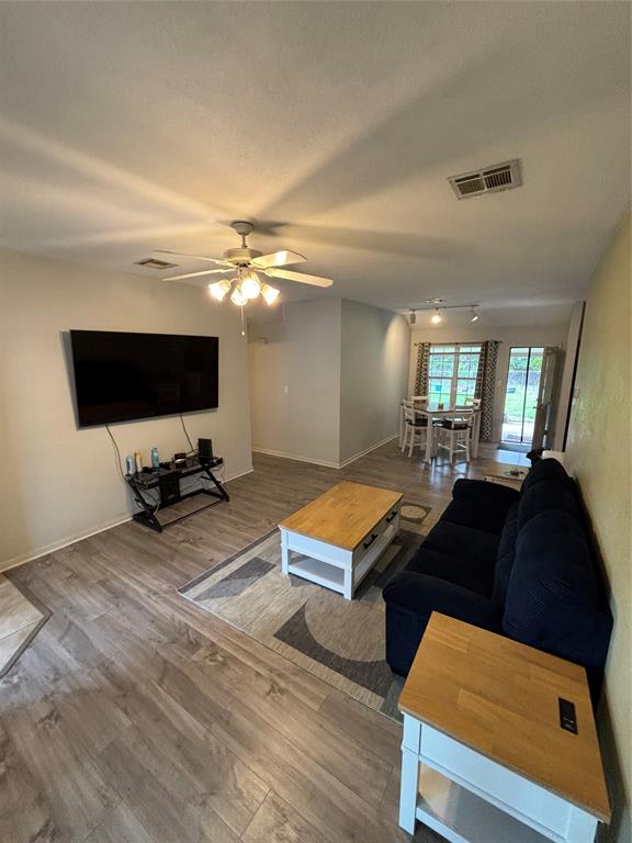 Open-concept interior featuring wood-finish flooring, and a multi-blade ceiling fan with integrated lighting. Open-concept interior featuring wood-finish flooring, and a multi-blade ceiling fan with integrated lighting.