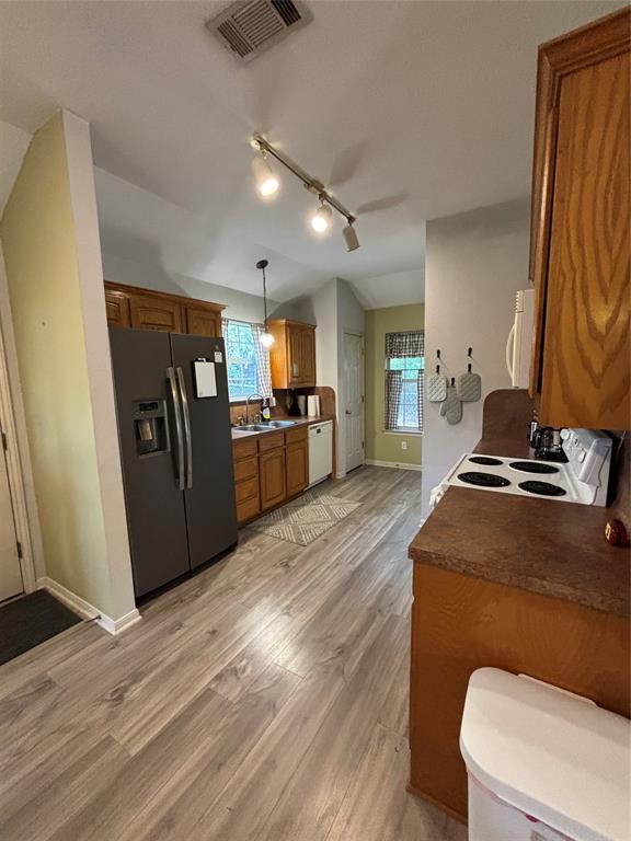 Kitchen featuring wood-finish cabinetry, solid surface countertops, wood-finish flooring, and track lighting Kitchen featuring wood-finish cabinetry, solid surface countertops, wood-finish flooring, and track lighting
