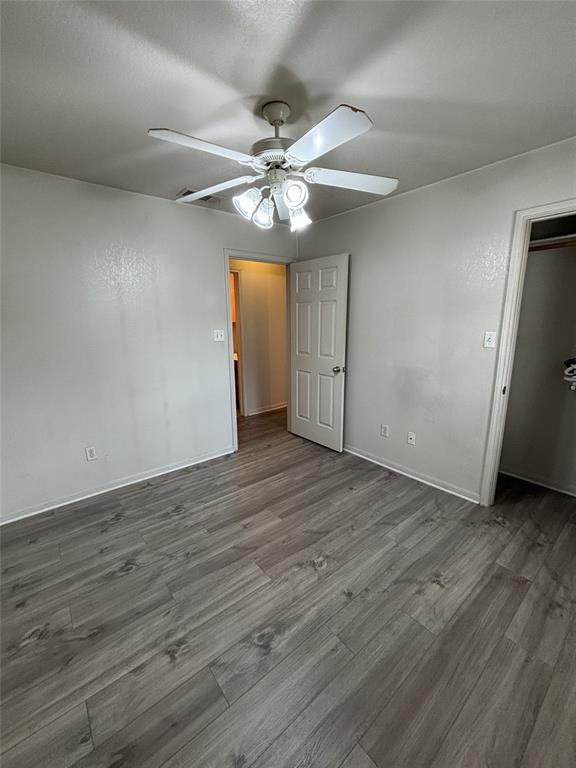 Room featuring wood-finish flooring, a neutral wall palette, and a multi-light ceiling fan.