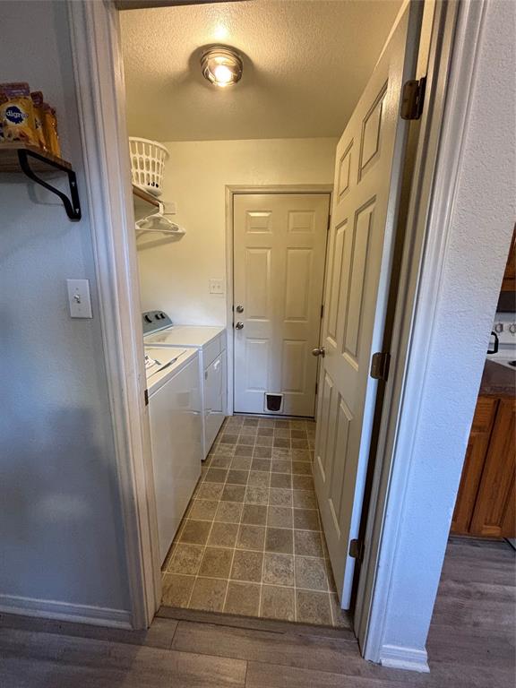 Utility space featuring tile flooring, built-in shelving, a dedicated laundry area, and an exterior door with an integrated pet portal