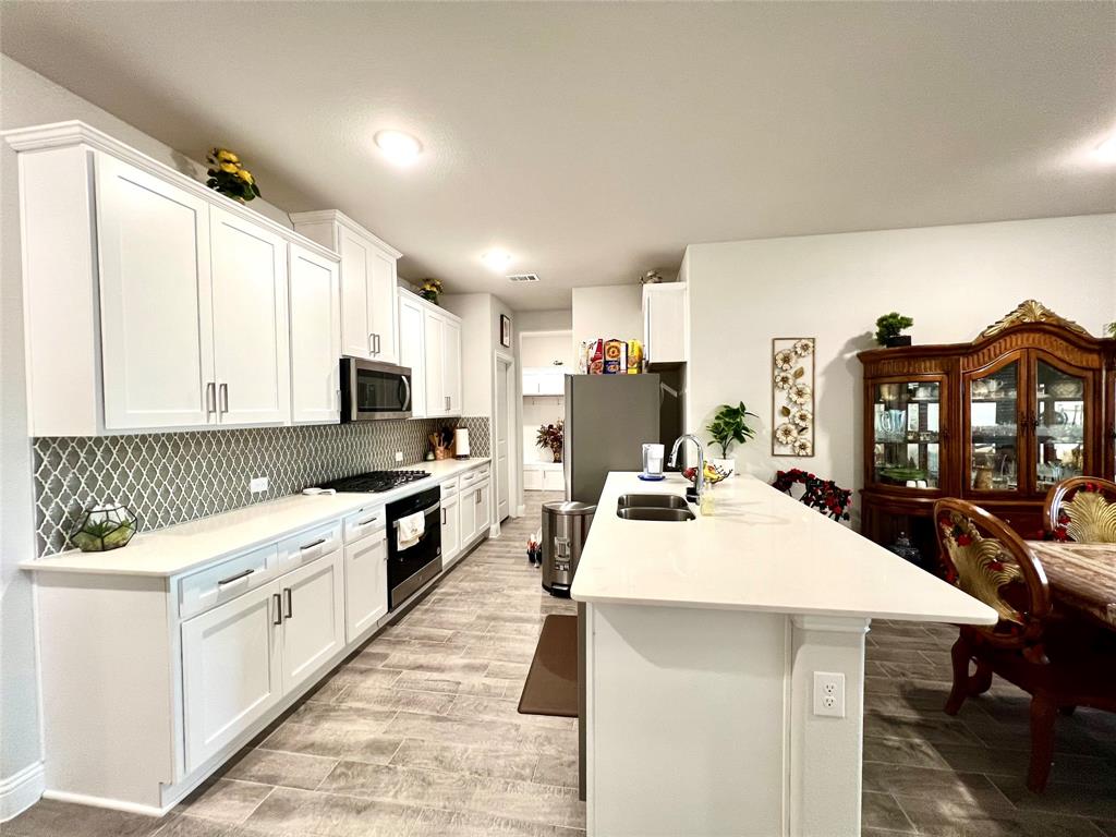 Kitchen with sink, white cabinets, a kitchen bar, stainless steel appliances, and backsplash
