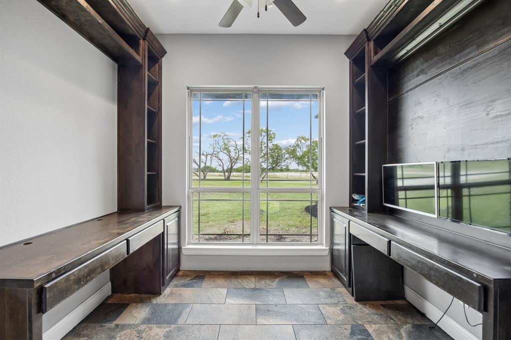 Custom built-in wood cabinetry with integrated shelving and desk surfaces, tile flooring, and a large dual-pane window