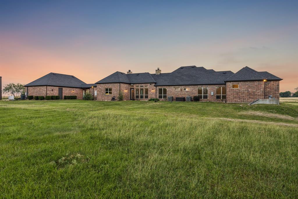 Single-story brick exterior featuring a multi-gable roofline, numerous multi-pane windows, and an expansive surrounding lawn