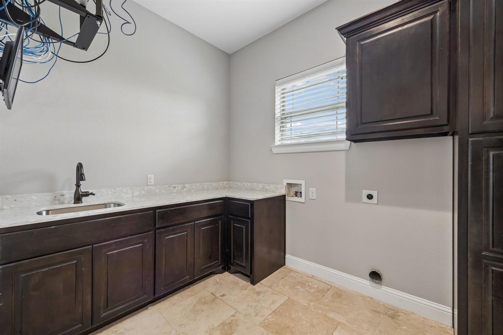 Dark wood cabinetry, stone-finish countertops, drop-in sink with a high-arch faucet, and tile flooring