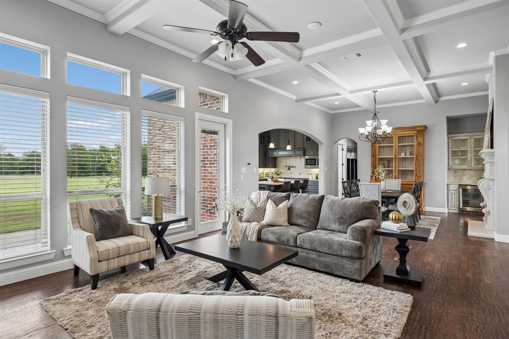 Coffered ceilings with recessed lighting, dark wood-finish flooring, floor-to-ceiling windows, and a built-in stone fireplace mantle