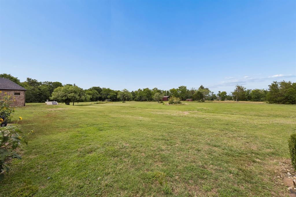 Expansive open acreage featuring mature trees, peripheral wooded area, and masonry exterior structure