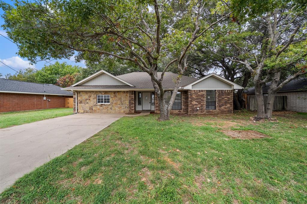 Single-story exterior featuring a stone and brick facade, gabled rooflines, concrete driveway, and mature landscaping Single-story exterior featuring a stone and brick facade, gabled rooflines, concrete driveway, and mature landscaping