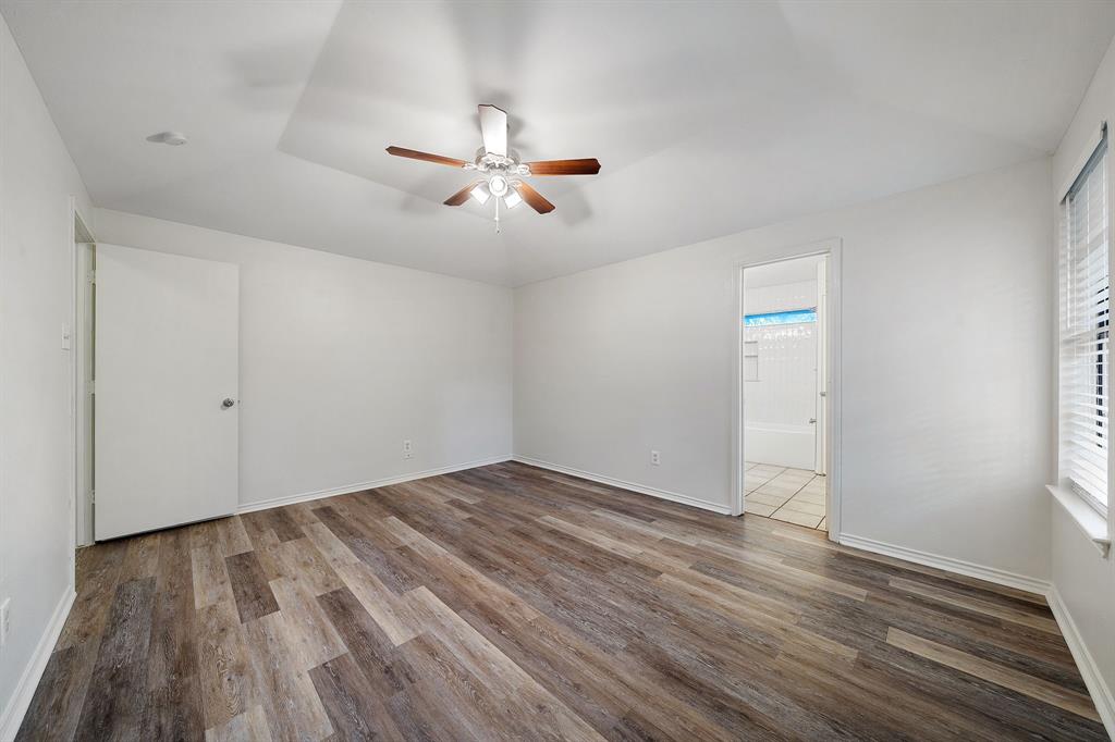 Tray ceiling featuring a center-mounted ceiling fan with light fixture, wood-finish flooring, and white horizontal window blinds