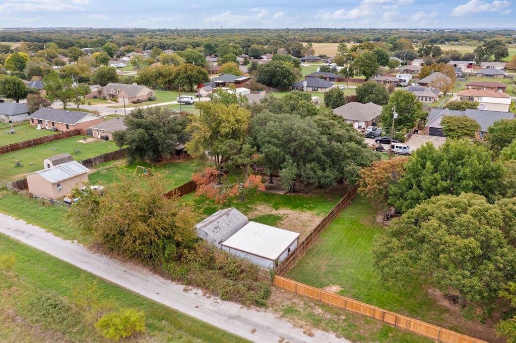Expansive lot featuring mature trees, wood privacy fencing, and two detached storage structures