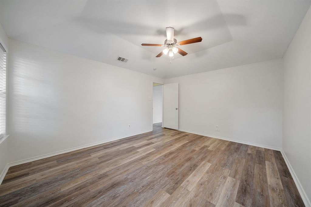 Room featuring vaulted ceilings, wood-finish flooring, and a central ceiling fan with integrated lighting