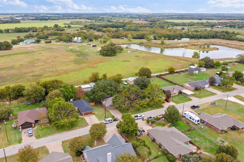 Aerial perspective of a sprawling landscape featuring expansive green acreage, mature trees, and a natural pond