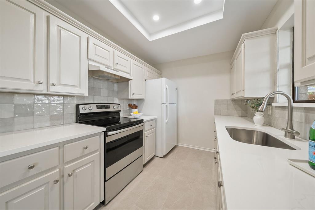 Kitchen featuring crisp white shaker-style cabinetry, solid-surface countertops, a tiled backsplash, stainless steel range, and recessed ceiling lighting
