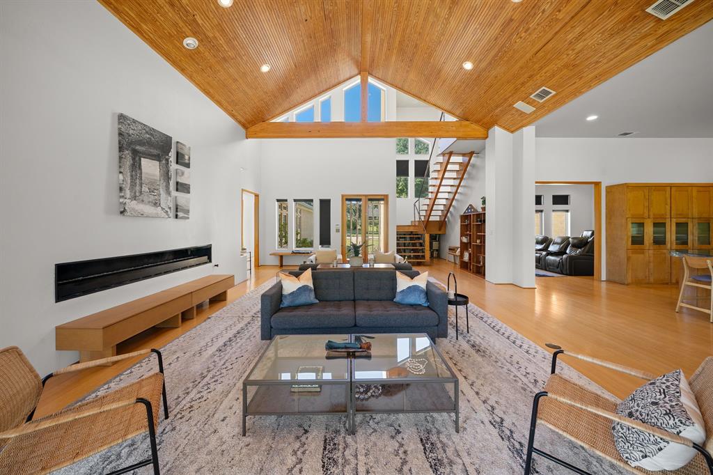 Vaulted wood-plank ceiling, horizontal linear fireplace, wood-finish flooring, built-in cabinetry, and open staircase with wood steps