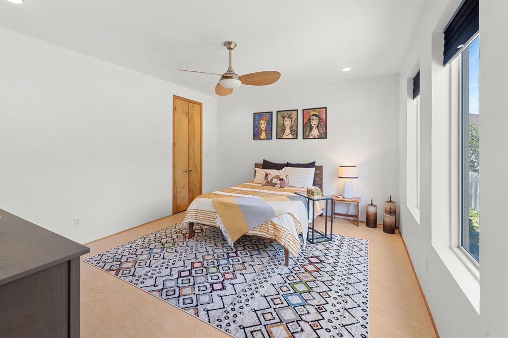Neutral-toned room featuring a minimalist ceiling fan with an integrated light fixture, clean-finish wood interior door, and tall vertical windows