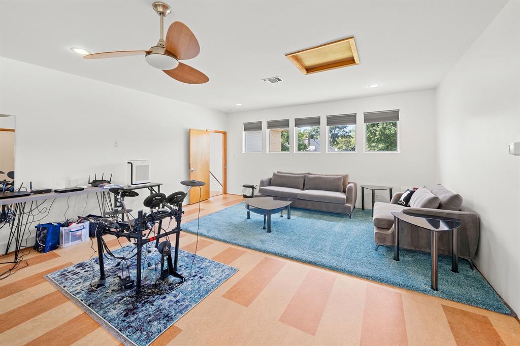 Expansive room featuring multi-tonal wood-finish flooring, recessed lighting, a ceiling fan, and a series of five rectangular windows with fitted shades