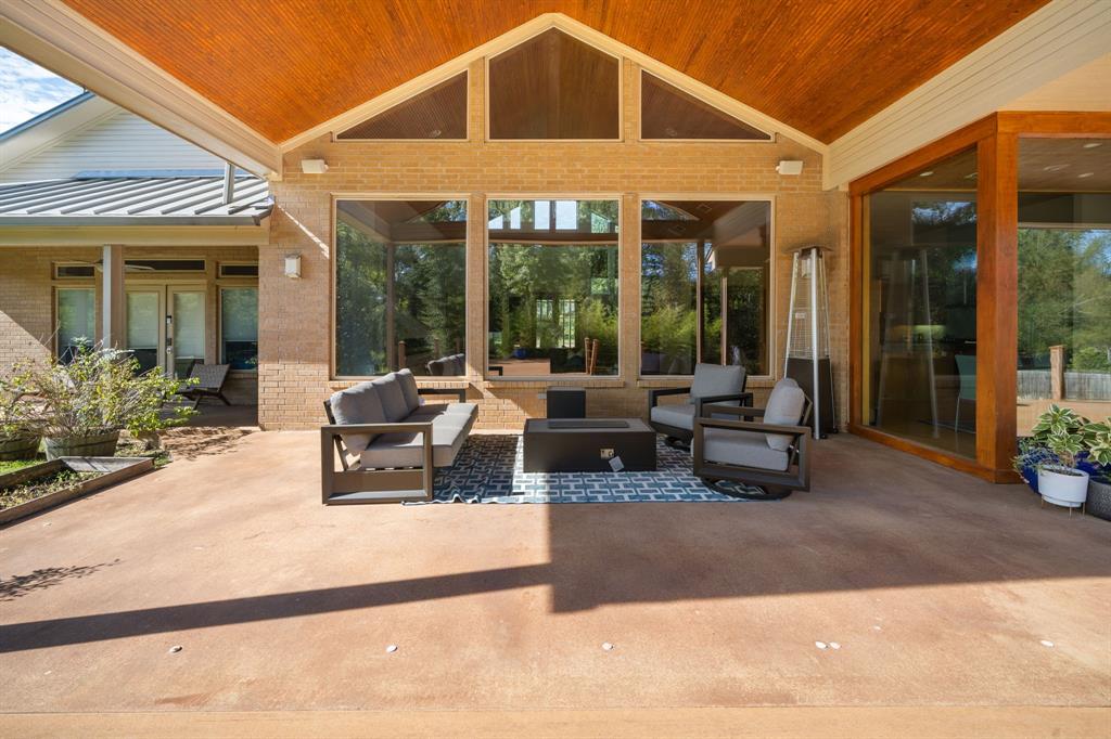 Covered outdoor patio featuring a vaulted tongue-and-groove wood ceiling, large picture windows, recessed lighting, and brick exterior walls